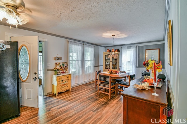 dining room featuring hardwood / wood-style floors, ceiling fan with notable chandelier, a textured ceiling, and ornamental molding