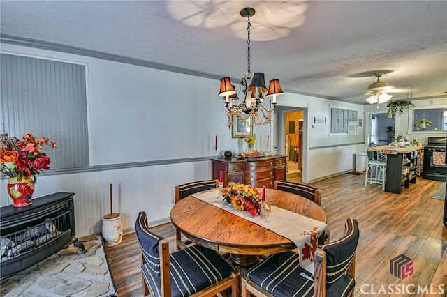 dining area with hardwood / wood-style floors, ceiling fan with notable chandelier, ornamental molding, and a textured ceiling