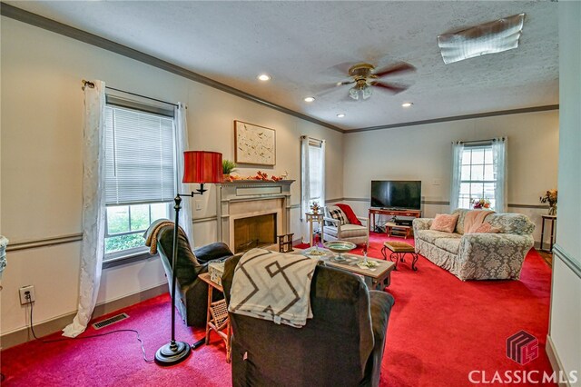 living room featuring a textured ceiling, ceiling fan, carpet floors, and ornamental molding