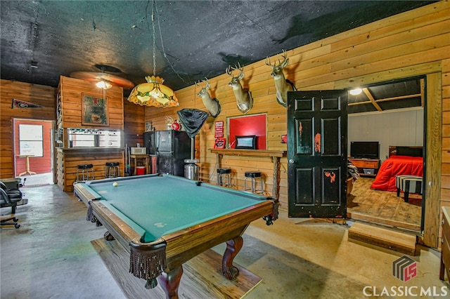 playroom with wood walls, concrete flooring, and pool table