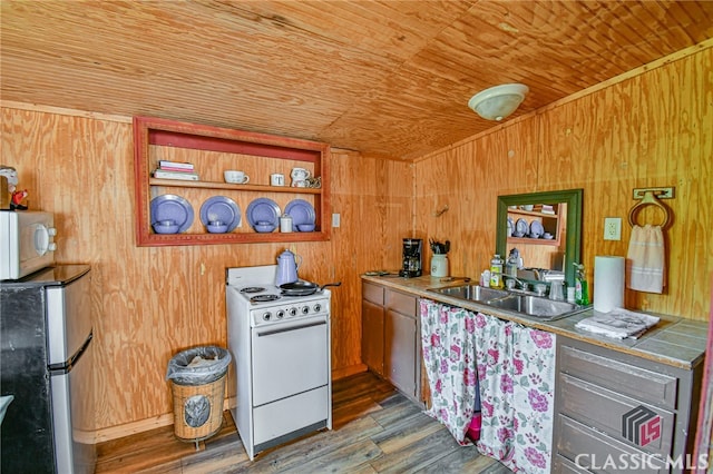 kitchen with wooden walls, sink, hardwood / wood-style floors, and white appliances