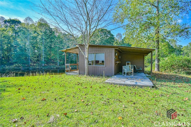 back of property with a yard, a water view, and an outbuilding