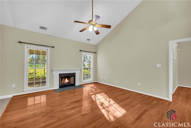 unfurnished living room featuring light hardwood / wood-style flooring, high vaulted ceiling, a wealth of natural light, and ceiling fan