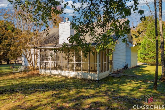 view of side of property with a sunroom and a yard