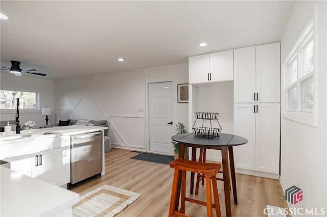 kitchen with white cabinets, dishwasher, ceiling fan, and light wood-type flooring