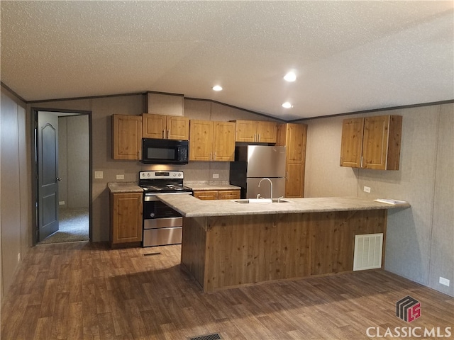 kitchen featuring kitchen peninsula, appliances with stainless steel finishes, a textured ceiling, dark hardwood / wood-style floors, and lofted ceiling