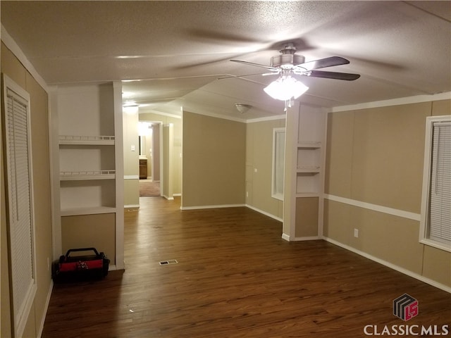 spare room with ceiling fan, dark hardwood / wood-style flooring, built in features, crown molding, and a textured ceiling