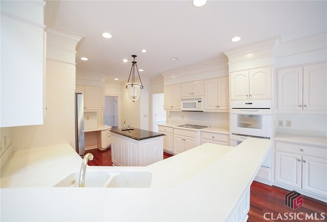 kitchen featuring pendant lighting, a center island, appliances with stainless steel finishes, dark hardwood / wood-style flooring, and white cabinetry