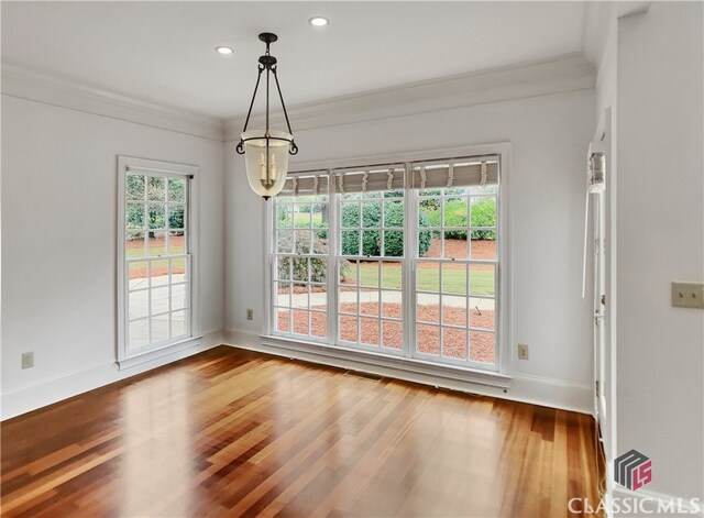 unfurnished dining area featuring wood-type flooring and crown molding