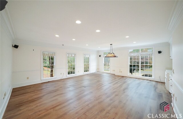 unfurnished living room with light hardwood / wood-style floors, crown molding, and a healthy amount of sunlight