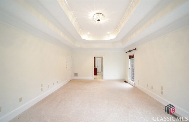 unfurnished room with carpet, a raised ceiling, and crown molding