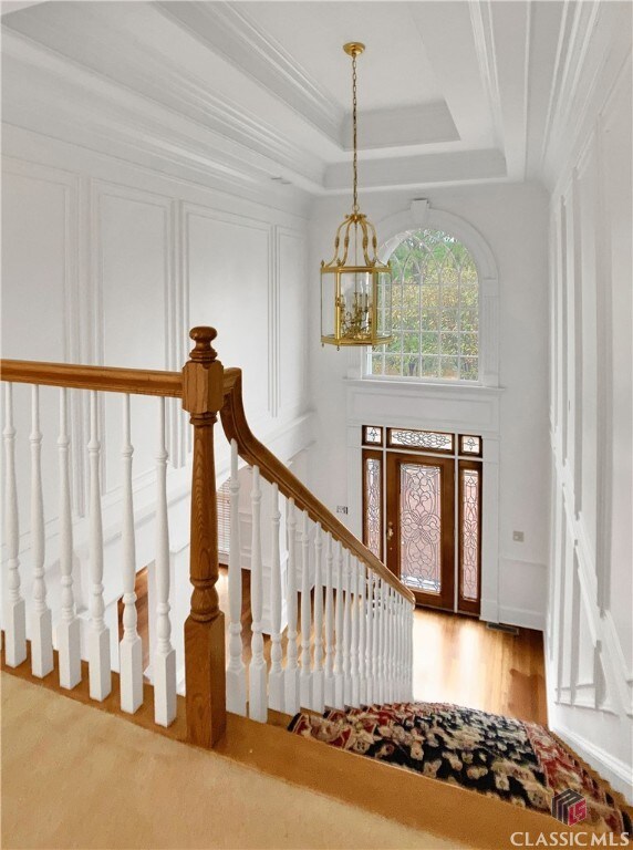 entryway with hardwood / wood-style floors, an inviting chandelier, crown molding, and a tray ceiling