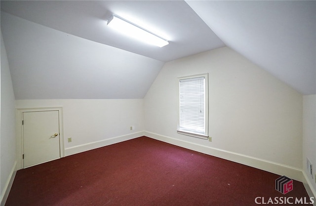 additional living space featuring carpet flooring and vaulted ceiling