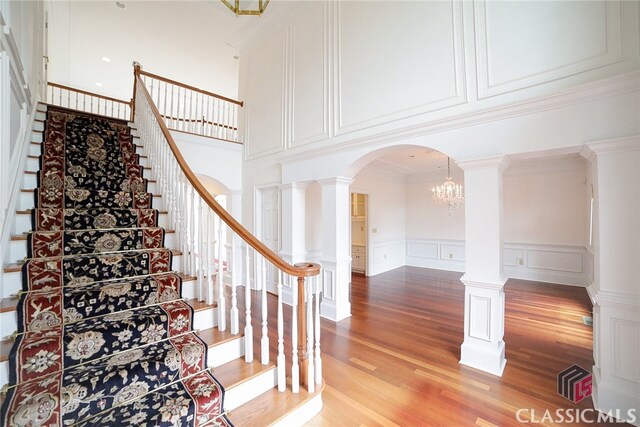 stairs with hardwood / wood-style floors, ornamental molding, and a high ceiling