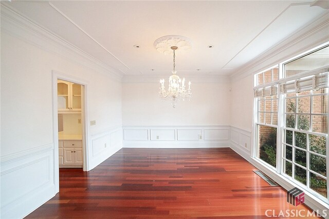 unfurnished dining area featuring crown molding, dark wood-type flooring, and a notable chandelier