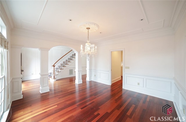 empty room featuring a chandelier, dark hardwood / wood-style floors, and ornamental molding