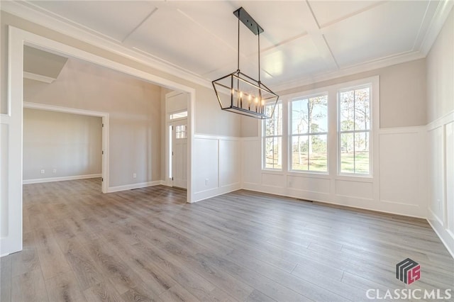 unfurnished dining area with hardwood / wood-style floors, a notable chandelier, and ornamental molding