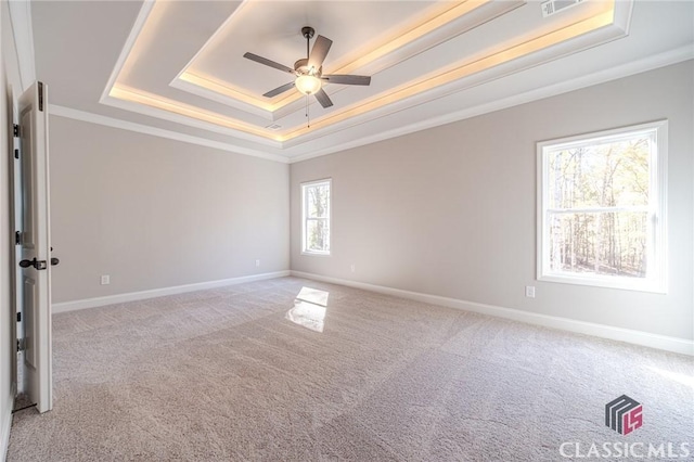 unfurnished bedroom featuring ornamental molding, a tray ceiling, ceiling fan, and light colored carpet