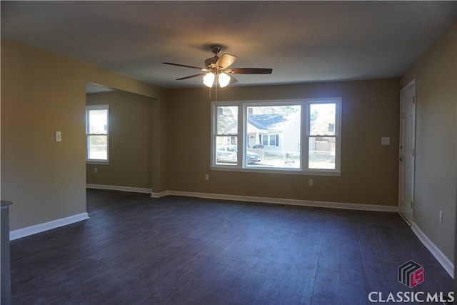 unfurnished room with plenty of natural light, dark wood-type flooring, and ceiling fan