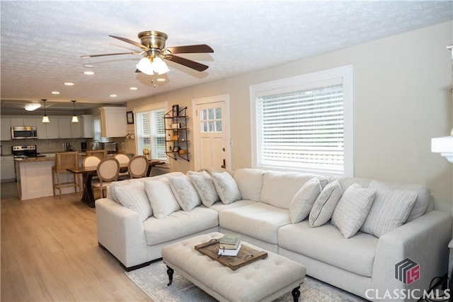 dining area with light hardwood / wood-style floors, a textured ceiling, a wealth of natural light, and a brick fireplace