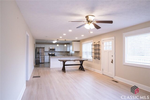 living room featuring a textured ceiling, light hardwood / wood-style floors, and ceiling fan