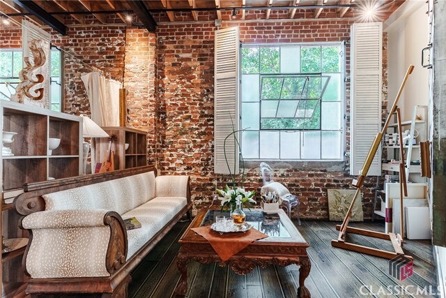 living room with hardwood / wood-style flooring and brick wall