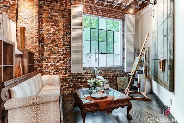 sitting room with hardwood / wood-style flooring and brick wall