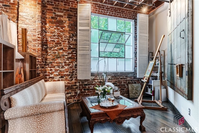 living area featuring brick wall and hardwood / wood-style floors