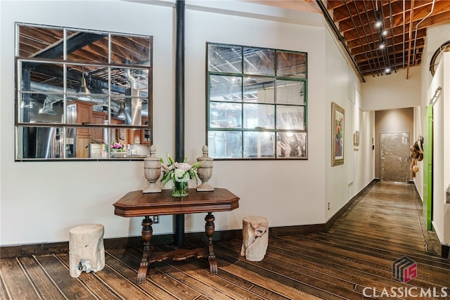 hallway featuring a high ceiling, rail lighting, and dark hardwood / wood-style floors