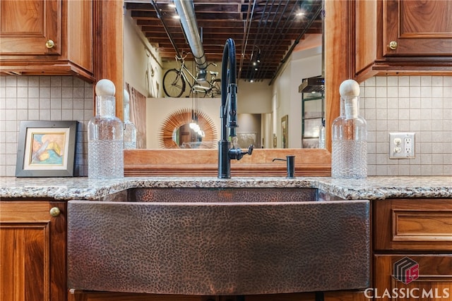 room details with wet bar, tasteful backsplash, and light stone countertops