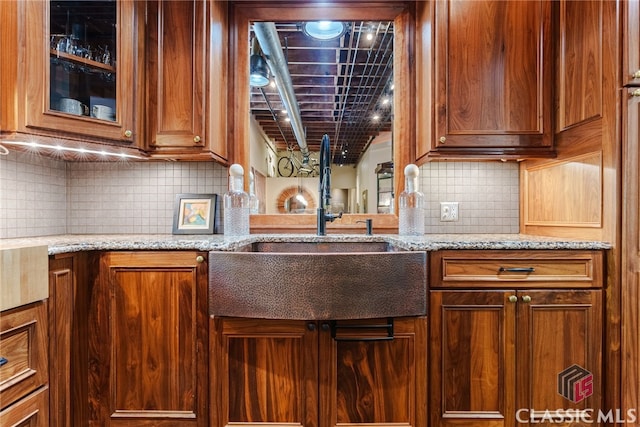 kitchen featuring sink, backsplash, and light stone counters