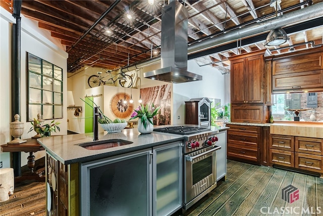 kitchen with a center island with sink, island range hood, high end stove, sink, and dark hardwood / wood-style floors