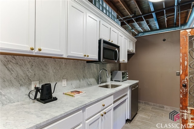 kitchen featuring appliances with stainless steel finishes, tasteful backsplash, light stone counters, sink, and white cabinetry