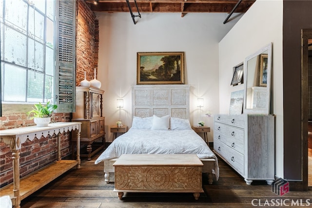 bedroom featuring beam ceiling, a high ceiling, and dark hardwood / wood-style floors