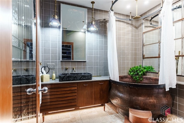 bathroom with tile patterned flooring, tile walls, vanity, walk in shower, and decorative backsplash