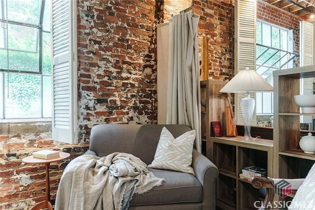 sitting room with a healthy amount of sunlight and brick wall