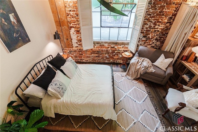 bedroom with brick wall and wood-type flooring