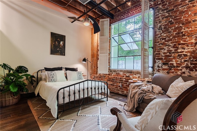 bedroom with hardwood / wood-style floors, brick wall, and beam ceiling