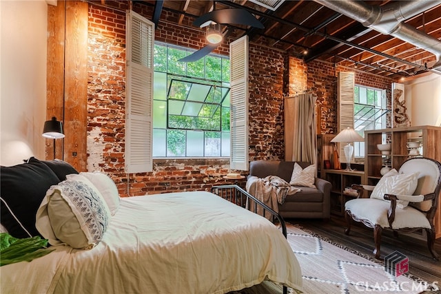 bedroom featuring hardwood / wood-style flooring and brick wall