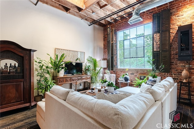 living room featuring brick wall, a towering ceiling, and dark hardwood / wood-style flooring