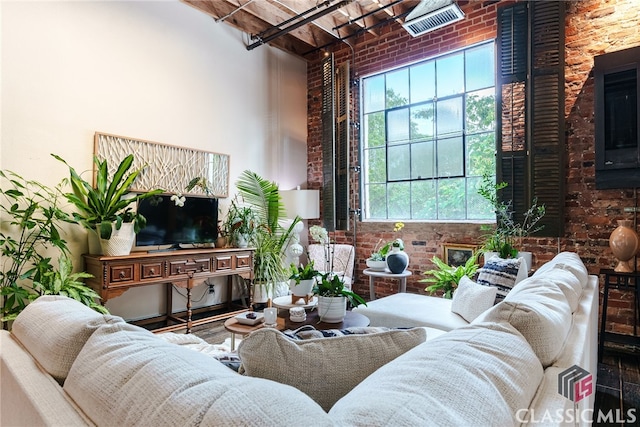 living room featuring brick wall, a high ceiling, and hardwood / wood-style floors