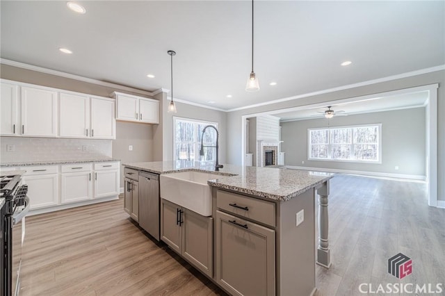 kitchen with sink, hanging light fixtures, white cabinets, and a kitchen island with sink