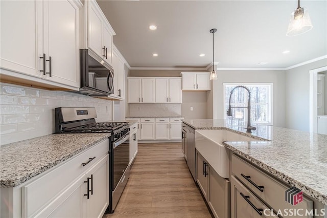 kitchen featuring stainless steel appliances, white cabinetry, decorative light fixtures, and light stone countertops