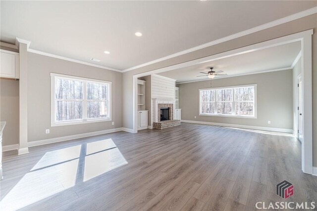 unfurnished living room with ceiling fan, a fireplace, ornamental molding, and light hardwood / wood-style floors