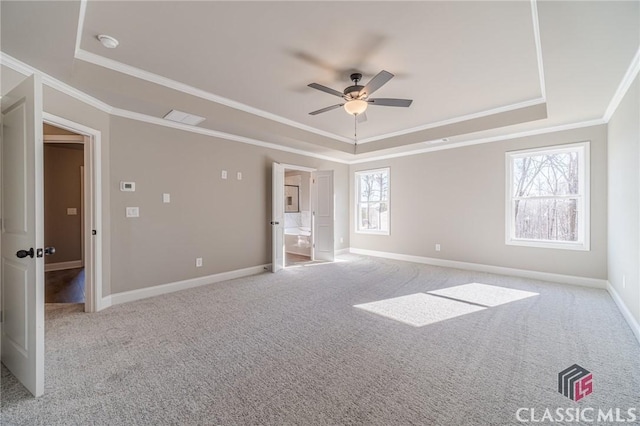 unfurnished bedroom featuring ceiling fan, a tray ceiling, ornamental molding, and light carpet