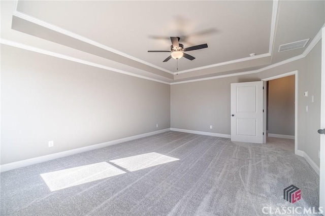 carpeted spare room with ceiling fan, a tray ceiling, and ornamental molding