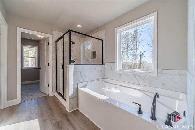 bathroom featuring wood-type flooring, shower with separate bathtub, and a healthy amount of sunlight