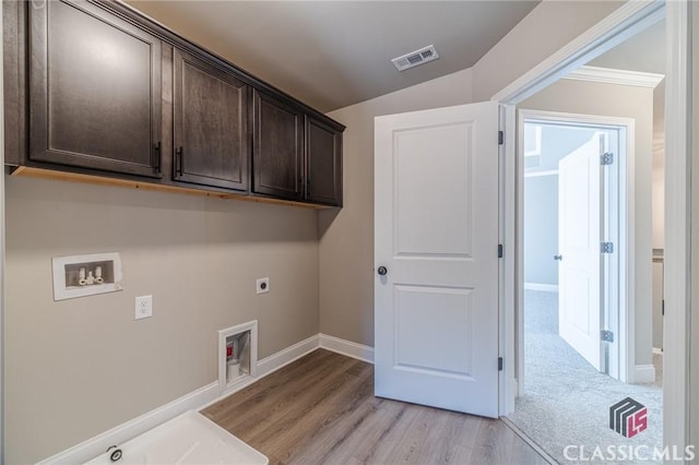 laundry area with cabinets, electric dryer hookup, hookup for a washing machine, light wood-type flooring, and crown molding