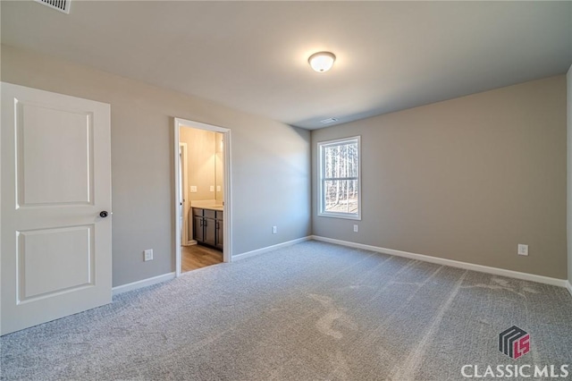 unfurnished bedroom with ensuite bathroom and light colored carpet