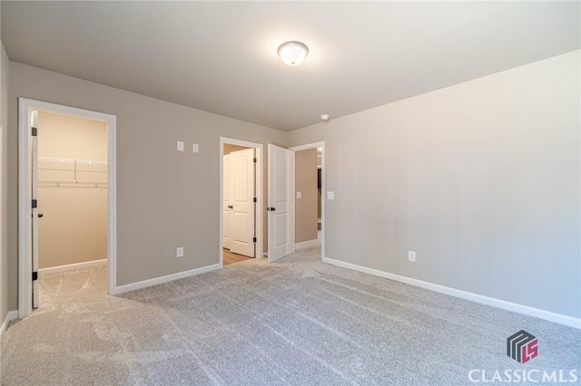 unfurnished bedroom featuring light carpet, a closet, and a walk in closet